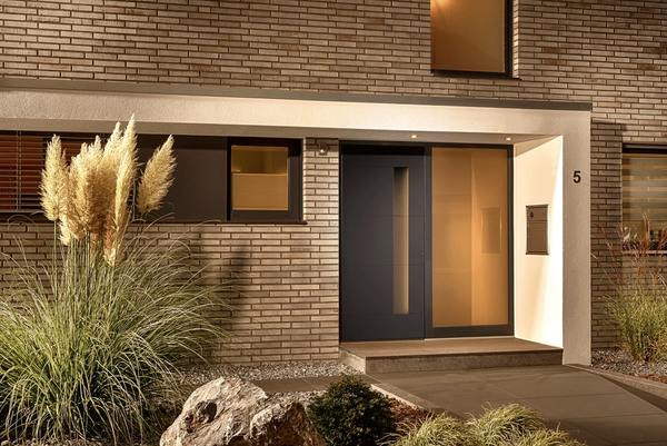 Moderne Haustür aus Glas und Aluminium mit Beleuchtung an einem Eingangsbereich.