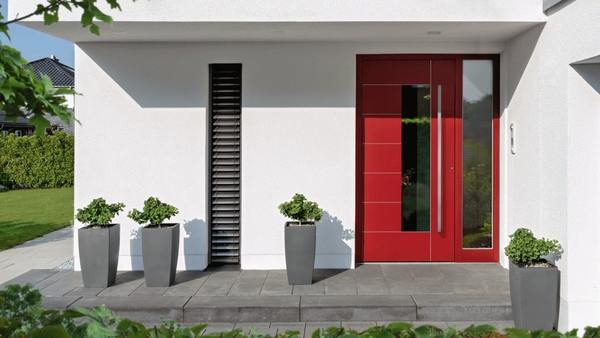 Moderne rote Haustür mit Seitenteil, graue Pflanzkübel und weiße Hausfassade im Eingangsbereich.